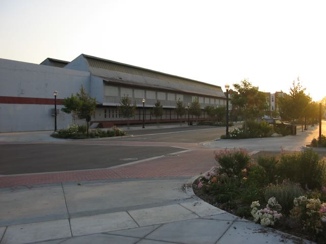 a photo of an old packing house with trees and new construction in the distance