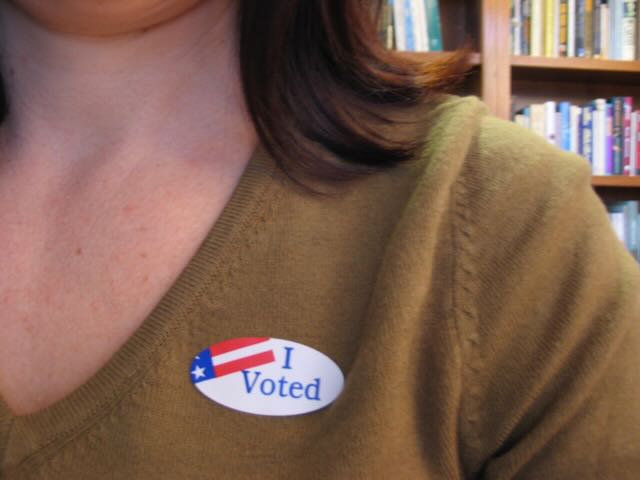 an 'I Voted' sticker on a brown sweater