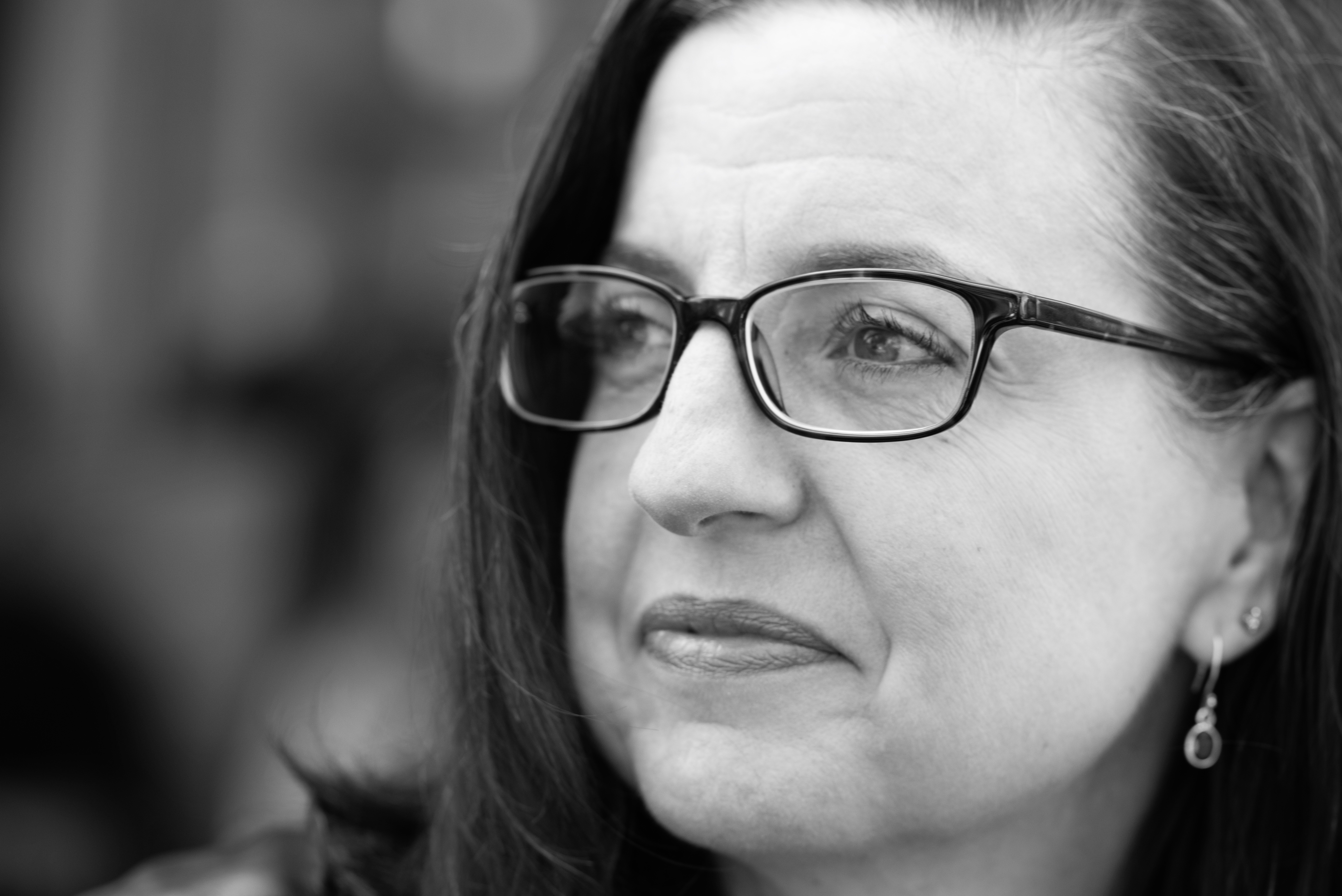 A 52 year old woman with glasses and greying dark hair, in left profile