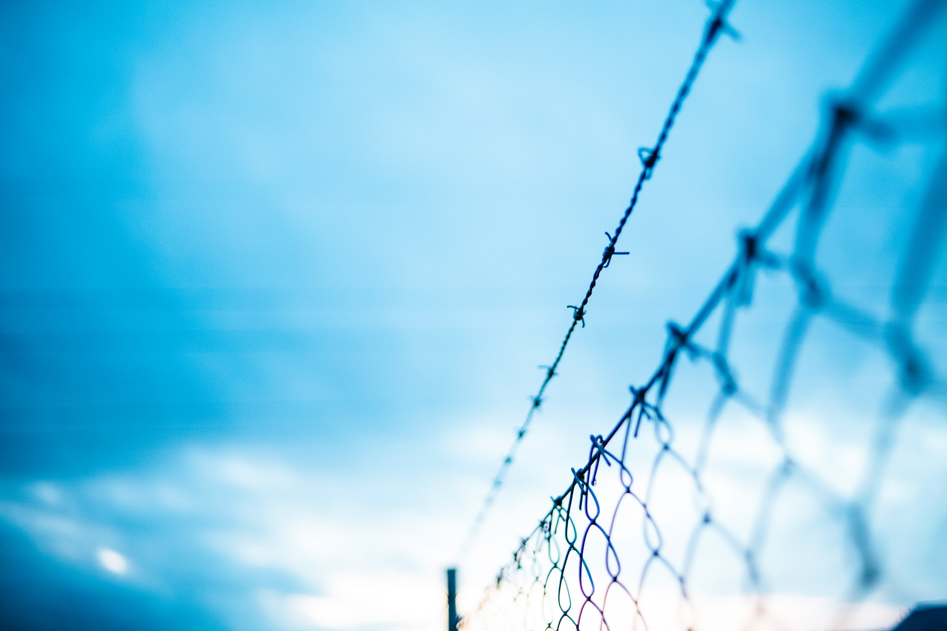 Photograph of a blue sky with the top of a wire fence on the right