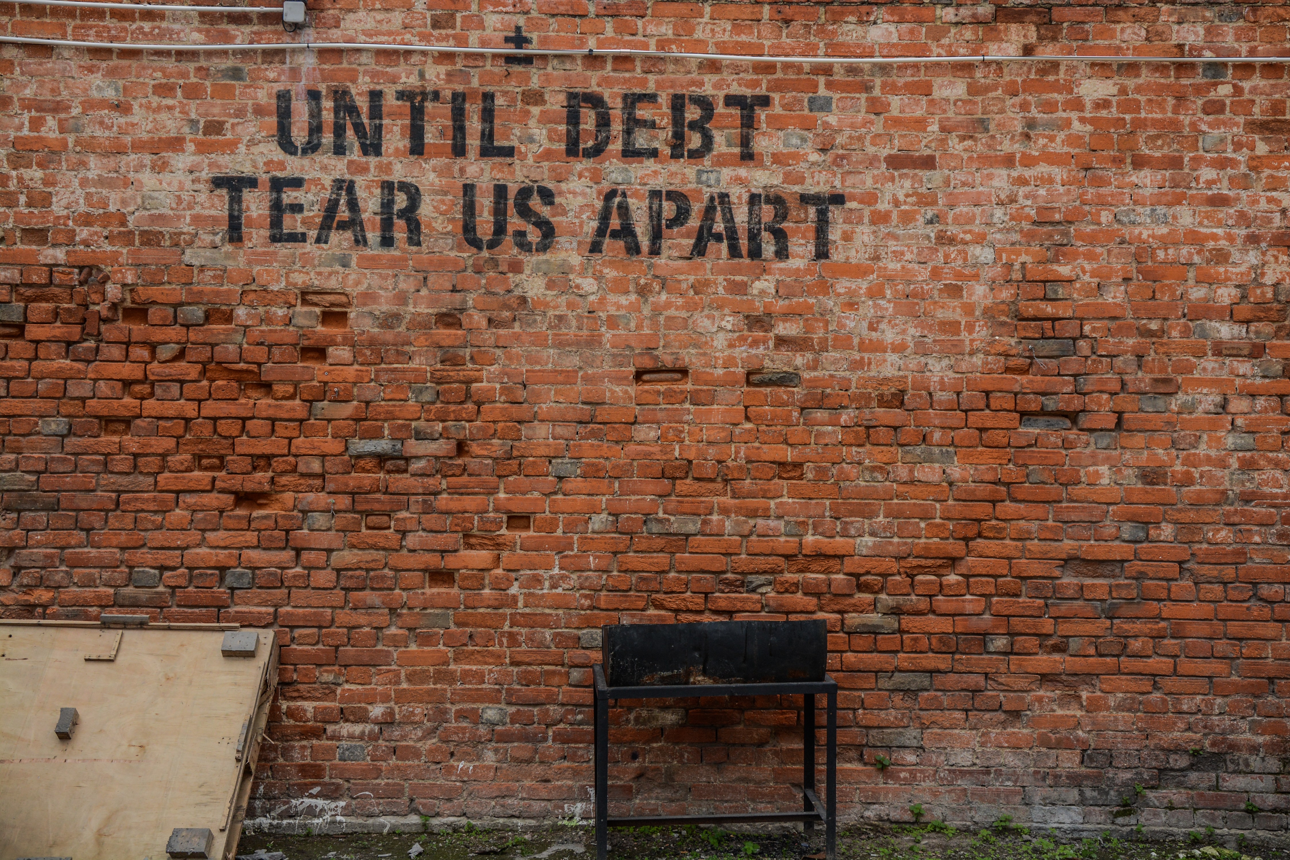 wall painted with "until debt tear us apart"